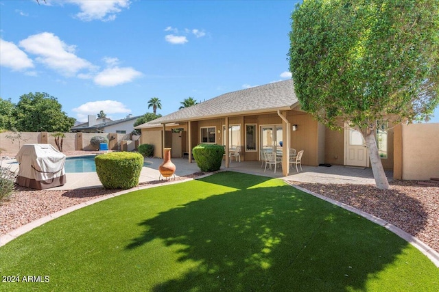 rear view of house featuring a fenced in pool, a yard, and a patio area