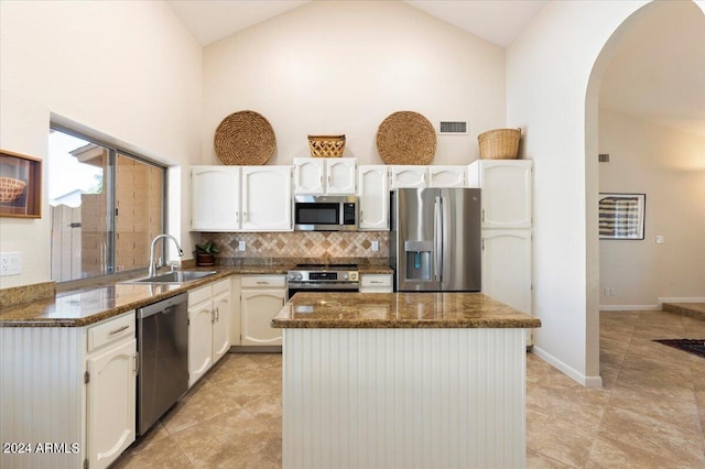 kitchen with white cabinets, sink, stainless steel appliances, dark stone counters, and decorative backsplash