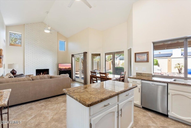 kitchen with sink, white cabinetry, high vaulted ceiling, a brick fireplace, and stainless steel dishwasher