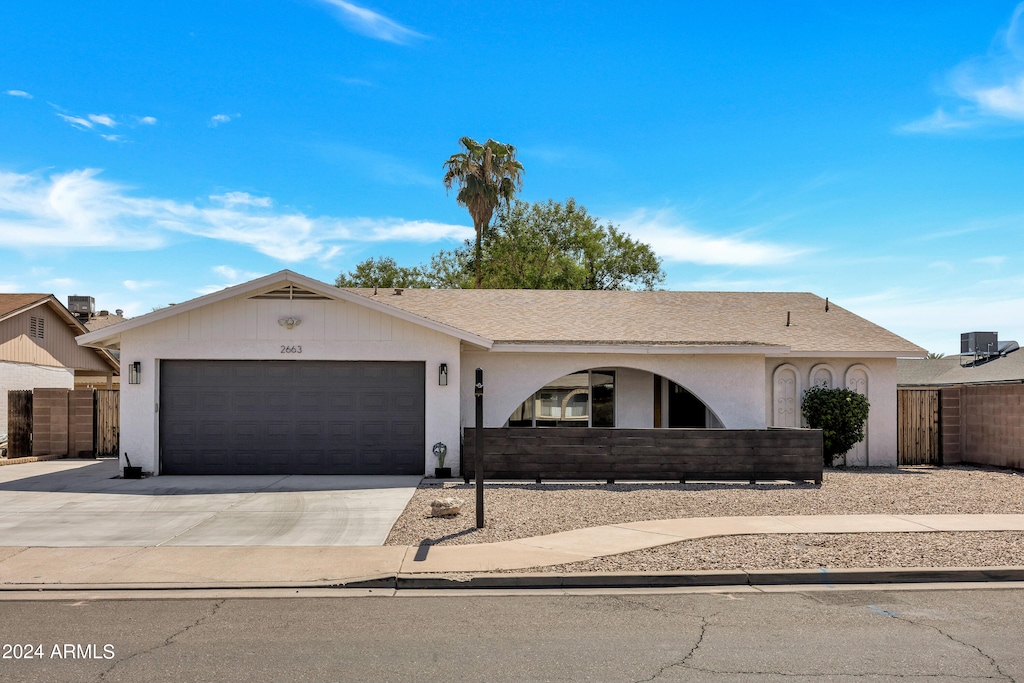 ranch-style house featuring a garage and cooling unit