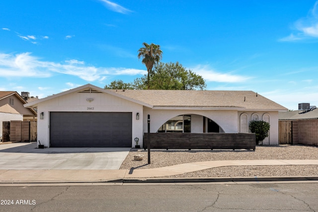 ranch-style house featuring a garage and cooling unit