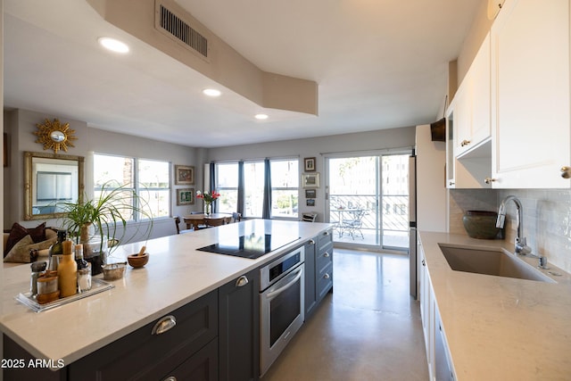kitchen with stainless steel oven, a sink, black electric cooktop, recessed lighting, and white cabinets