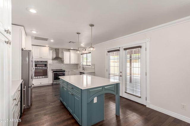 12241 N 49th Ave, Glendale, AZ 85304 - kitchen featuring wall chimney exhaust hood, appliances with stainless steel finishes, blue cabinets, white cabinetry, and a kitchen breakfast bar