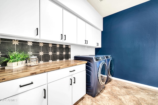 washroom with cabinets, light tile patterned flooring, and washer and dryer