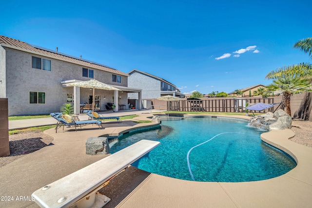 view of swimming pool with a diving board and a patio