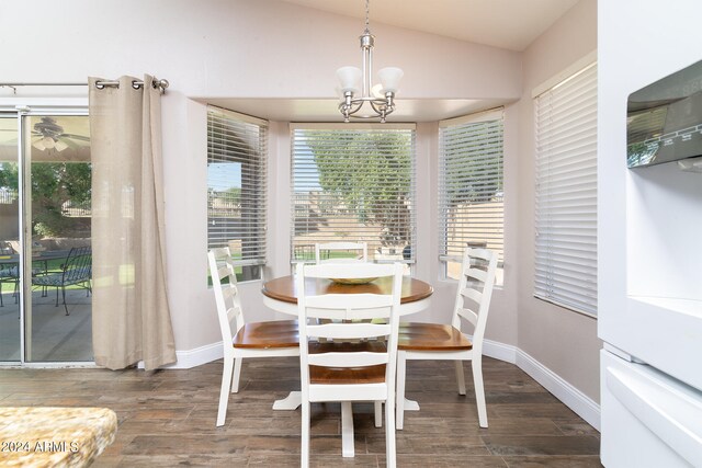 dining room featuring ceiling fan with notable chandelier, vaulted ceiling, and dark hardwood / wood-style flooring