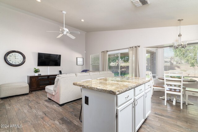 kitchen with dark hardwood / wood-style floors, white cabinets, a kitchen island, and decorative light fixtures