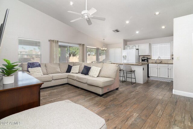 living room featuring ceiling fan with notable chandelier, high vaulted ceiling, dark wood-type flooring, and sink