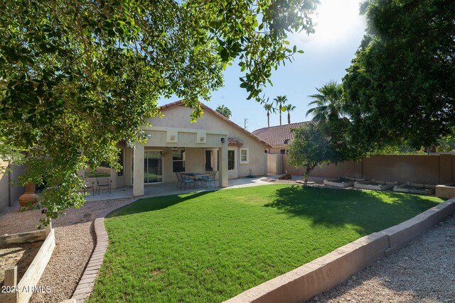 back of property with a yard and a patio