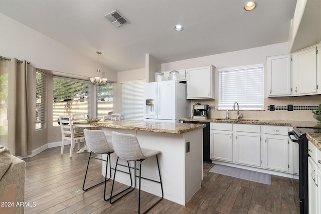 kitchen featuring a kitchen island, white refrigerator with ice dispenser, lofted ceiling, and white cabinets