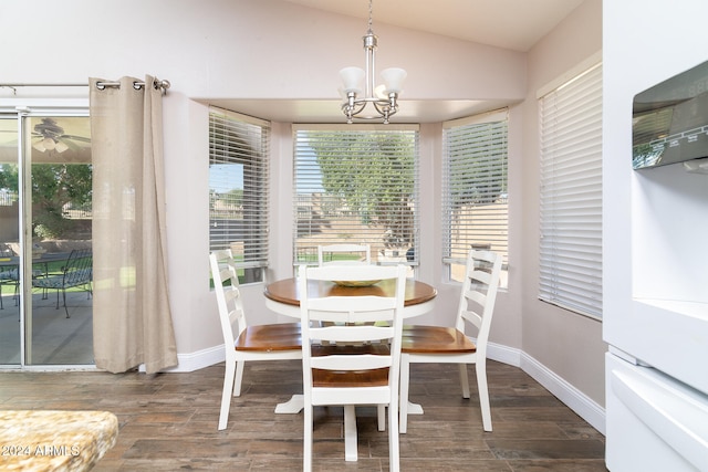 dining area with ceiling fan with notable chandelier, lofted ceiling, and dark hardwood / wood-style flooring