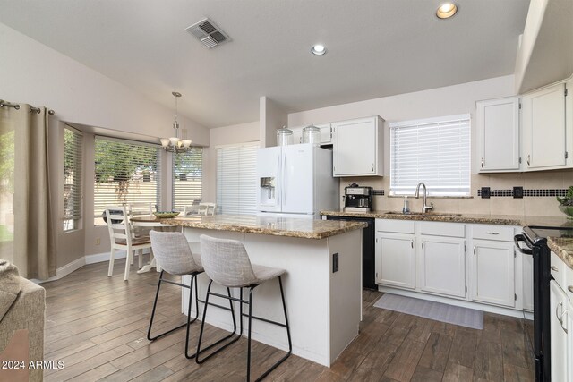 kitchen featuring white fridge with ice dispenser, white cabinets, lofted ceiling, and a kitchen island