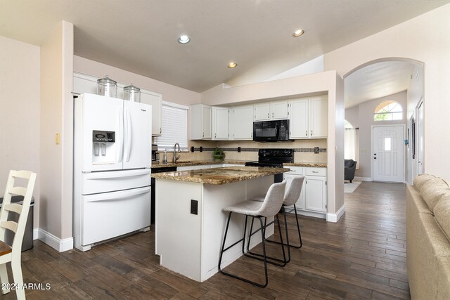 kitchen featuring dark stone countertops, lofted ceiling, white cabinets, black appliances, and a center island