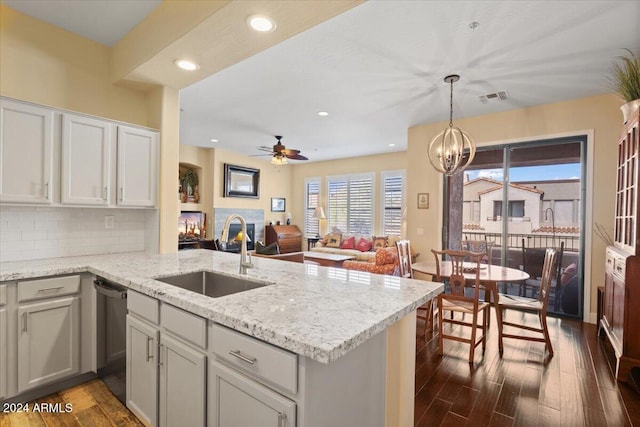 kitchen with ceiling fan with notable chandelier, decorative backsplash, sink, stainless steel dishwasher, and dark hardwood / wood-style floors