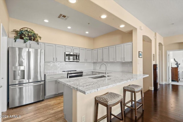 kitchen with a kitchen bar, stainless steel appliances, light hardwood / wood-style floors, kitchen peninsula, and sink