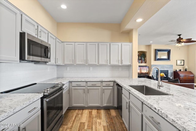 kitchen with tasteful backsplash, stainless steel appliances, sink, light hardwood / wood-style floors, and ceiling fan