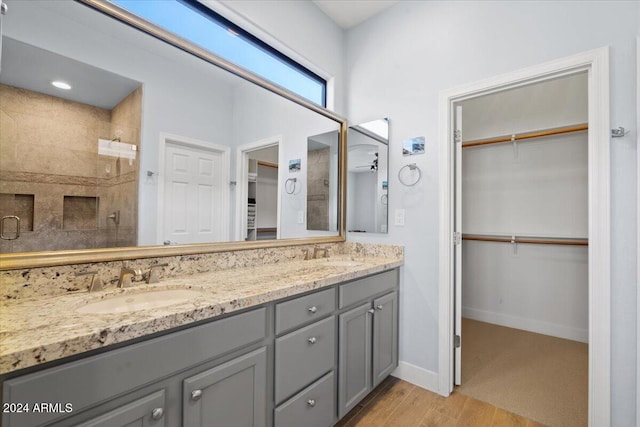 bathroom featuring hardwood / wood-style flooring, vanity, and tiled shower