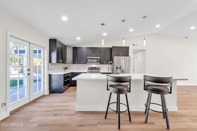 kitchen with a breakfast bar area, stainless steel appliances, french doors, decorative backsplash, and decorative light fixtures