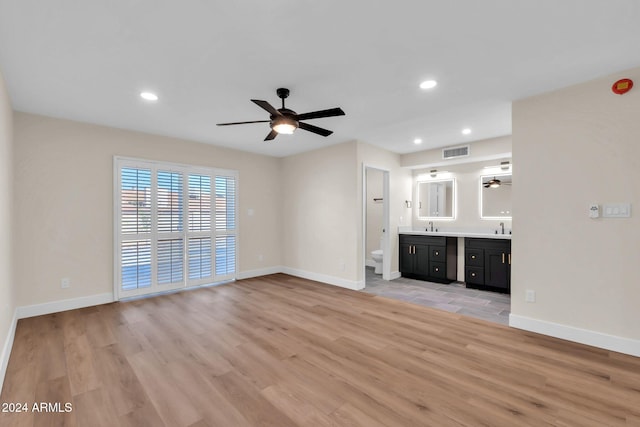 unfurnished living room with light wood-type flooring, ceiling fan, and sink