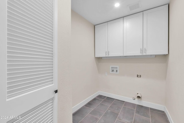 laundry area featuring hookup for a washing machine, cabinets, hookup for an electric dryer, gas dryer hookup, and dark tile patterned floors