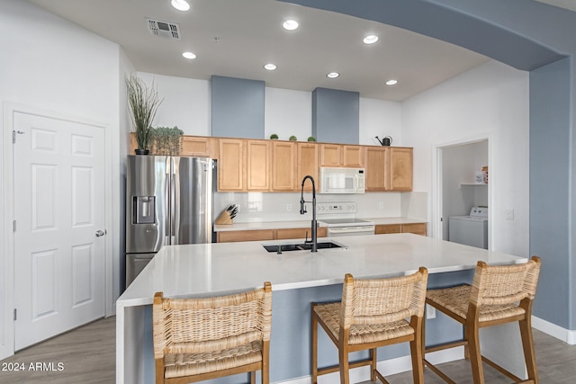 kitchen featuring stainless steel refrigerator with ice dispenser, a kitchen island with sink, dark wood-type flooring, electric stove, and washer / clothes dryer