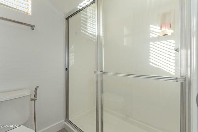 bathroom featuring toilet and a shower with door