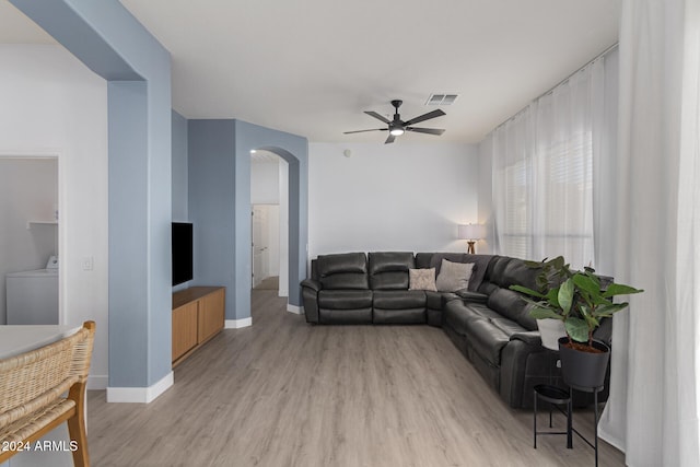 living room with washer / dryer, light hardwood / wood-style floors, and ceiling fan