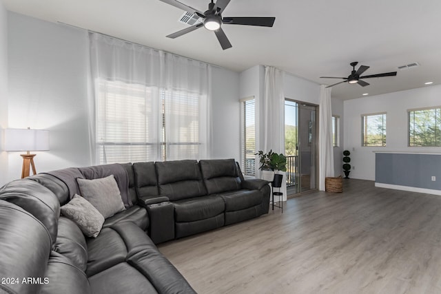 living room with light wood-type flooring, a wealth of natural light, and ceiling fan