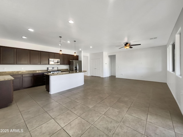 kitchen featuring appliances with stainless steel finishes, hanging light fixtures, light tile patterned floors, ceiling fan, and a center island with sink