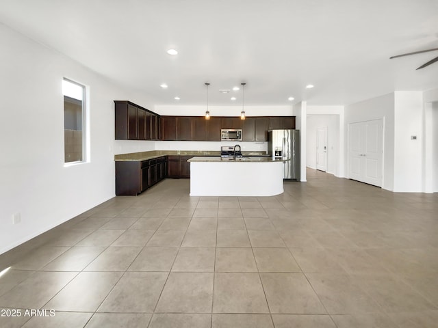 kitchen with appliances with stainless steel finishes, pendant lighting, sink, a kitchen island with sink, and light tile patterned floors