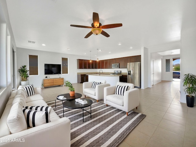 tiled living room featuring ceiling fan and sink