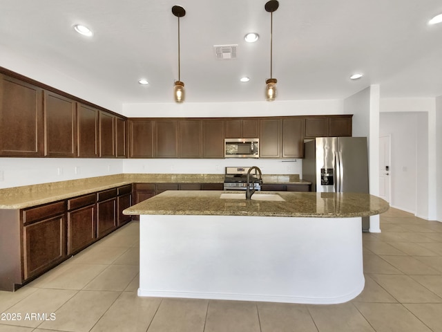 kitchen featuring appliances with stainless steel finishes, sink, hanging light fixtures, and a center island with sink