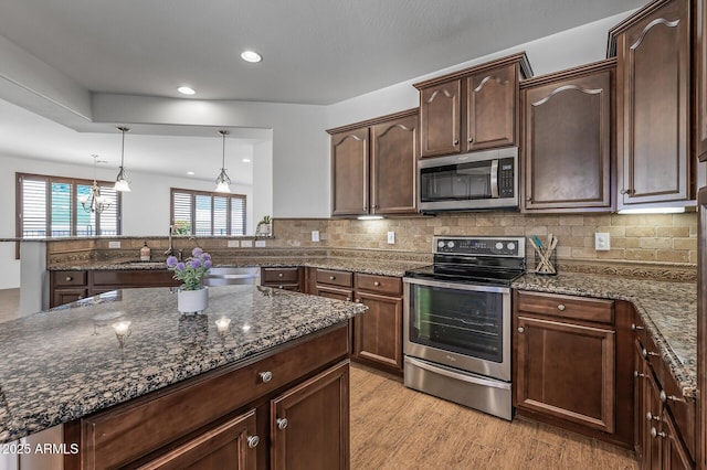 301 S 225th Ave, Buckeye, AZ 85326 - kitchen with stainless steel appliances, light wood-style floors, backsplash, and dark stone counters