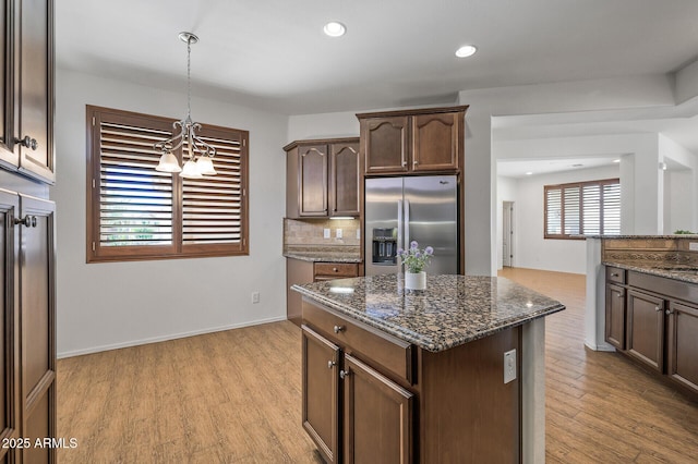 301 S 225th Ave, Buckeye, AZ 85326 - kitchen featuring stainless steel fridge with ice dispenser, dark stone countertops, a notable chandelier, backsplash, and light wood-style flooring