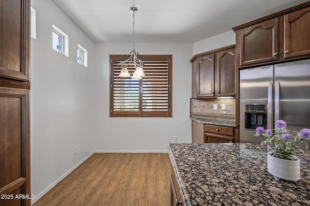 301 S 225th Ave, Buckeye, AZ 85326 - kitchen with dark stone countertops, stainless steel fridge, backsplash, decorative light fixtures, and light wood-style floors
