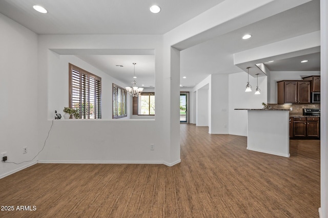 301 S 225th Ave, Buckeye, AZ 85326 - unfurnished living room featuring baseboards, recessed lighting, an inviting chandelier, and wood finished floors