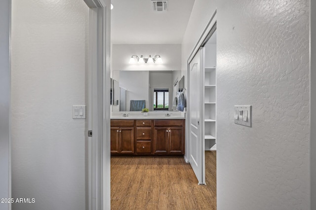 301 S 225th Ave, Buckeye, AZ 85326 - bathroom with visible vents, a sink, double vanity, a walk in closet, and wood finished floors