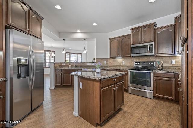 301 S 225th Ave, Buckeye, AZ 85326 - kitchen featuring tasteful backsplash, wood finished floors, a peninsula, and stainless steel appliances