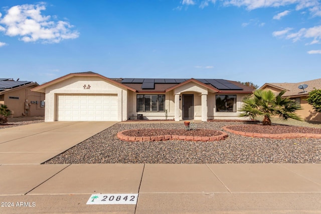 single story home featuring solar panels and a garage