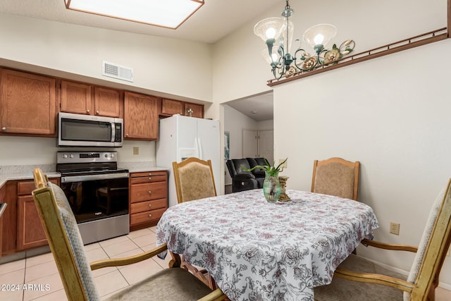 tiled dining area with a chandelier and high vaulted ceiling