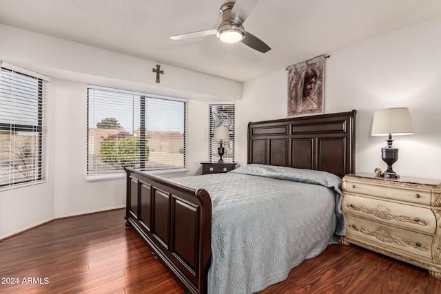 bedroom with a textured ceiling, multiple windows, dark wood-type flooring, and ceiling fan