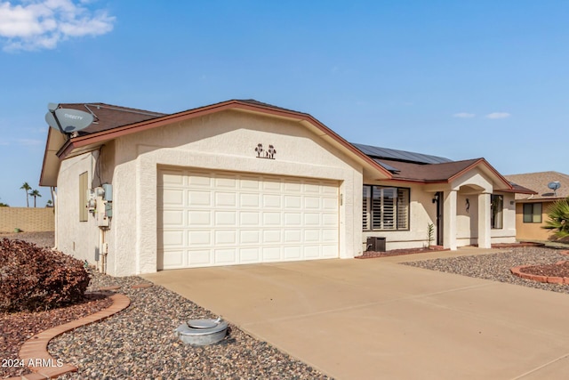 single story home with a garage and solar panels