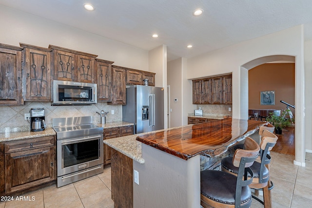 5077 E Lonesome Trl, Cave Creek, AZ 85331 - kitchen featuring stainless steel appliances, arched walkways, light tile patterned flooring, tasteful backsplash, and recessed lighting