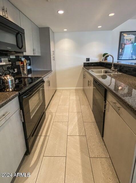 kitchen with black appliances, dark stone countertops, sink, backsplash, and light tile patterned floors