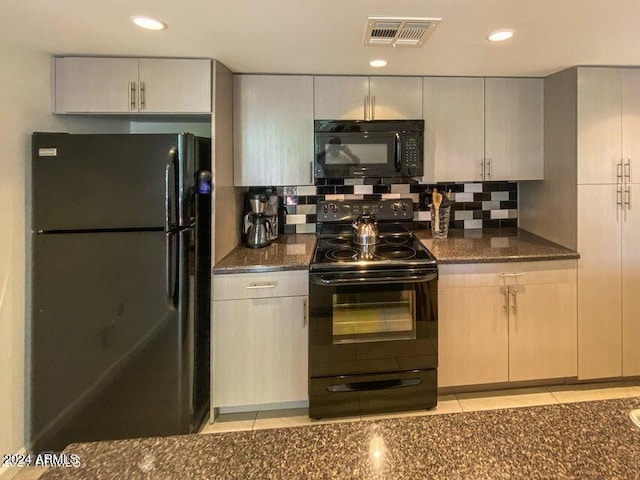 kitchen with light tile patterned floors, dark stone countertops, backsplash, and black appliances