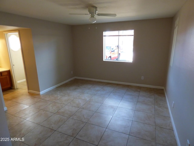 spare room featuring ceiling fan, light tile patterned floors, and baseboards