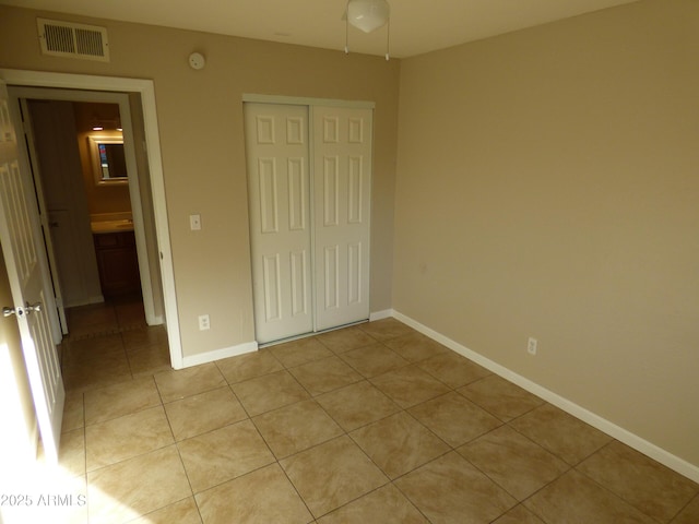 unfurnished bedroom featuring light tile patterned floors, a closet, and baseboards