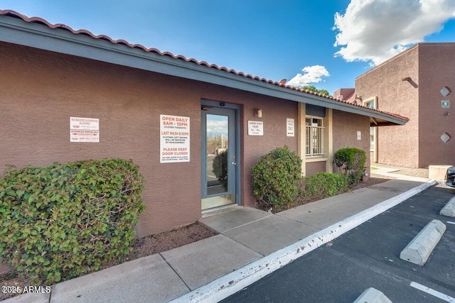 doorway to property with stucco siding and a tile roof