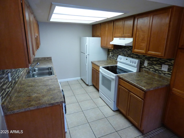 kitchen with white appliances, under cabinet range hood, a sink, tasteful backsplash, and brown cabinets