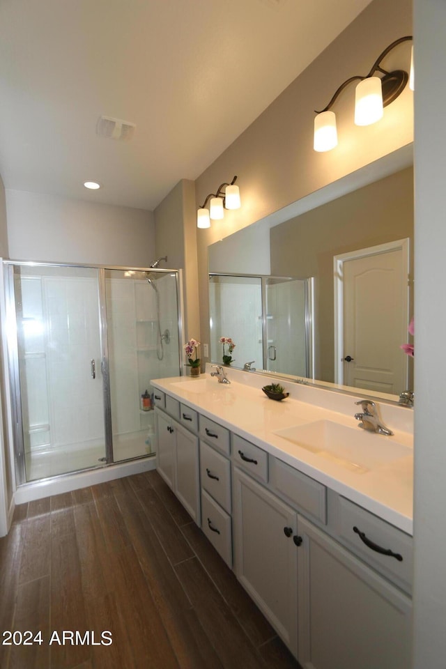 bathroom with wood-type flooring, vanity, and an enclosed shower